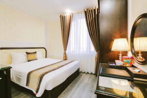 a bedroom with a bed and a desk and a mirror at Vincent Halong Hotel in Ha Long