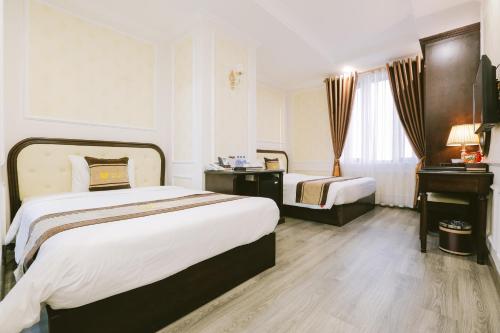 a hotel room with two beds and a desk at Vincent Halong Hotel in Ha Long