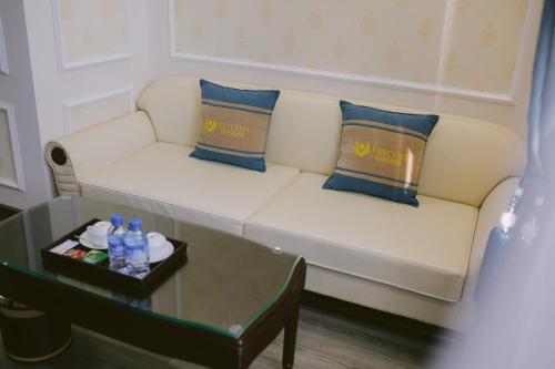 a white couch with two blue pillows and a table at Vincent Halong Hotel in Ha Long