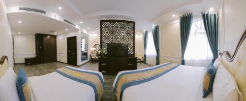 a bedroom with two beds and a television in it at Vincent Halong Hotel in Ha Long