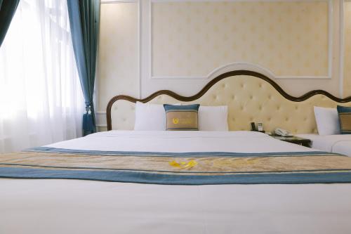 a bedroom with a large white bed with a wooden headboard at Vincent Halong Hotel in Ha Long
