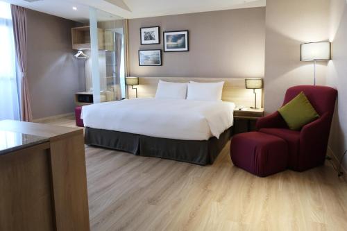 a hotel room with a bed and a red chair at The HO Hotel in Hsinchu City