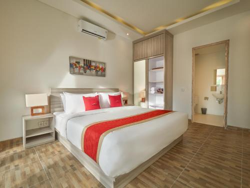 una camera da letto con un grande letto bianco con cuscini rossi di The Tempekan Nyang-Nyang a Uluwatu