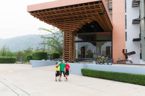 three people standing in front of a building at Zen Next Khao Yai By ZV in Pak Chong