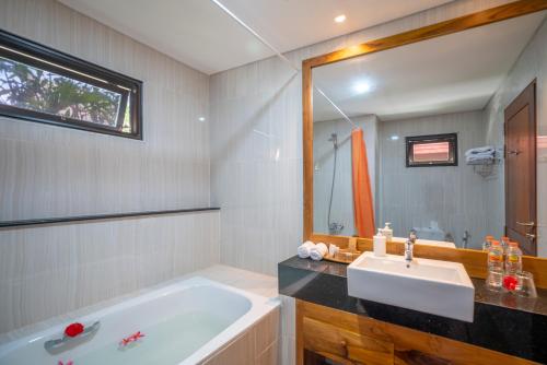 a bathroom with a tub and a sink and a mirror at The Salila Beach Resort in Seminyak