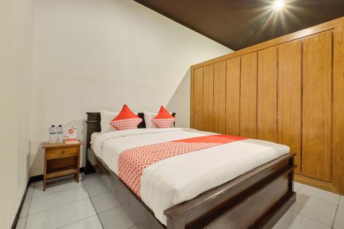 a bedroom with a large bed with a wooden headboard at Super OYO 2519 Mayang Garini in Magelang