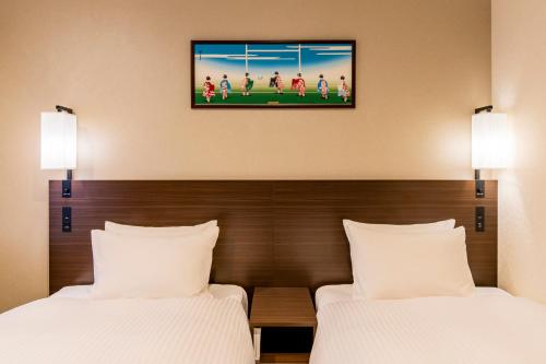 two beds in a hotel room with a tv on the wall at Kyoto Yamashina Hotel Sanraku in Kyoto