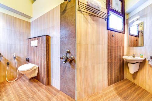a bathroom with a toilet a sink and a shower at FabExpress Nestlay Rooms in Chennai