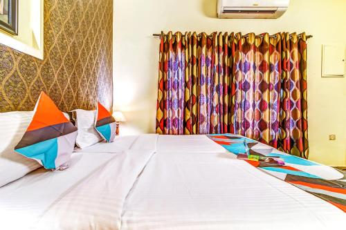 a bedroom with a white bed with colorful curtains at FabExpress Nestlay Rooms in Chennai