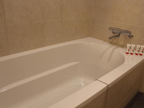 a white bath tub with a faucet in a bathroom at THE BLOSSOM HIBIYA in Tokyo