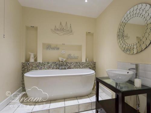 a bathroom with a tub and a sink and a mirror at Baytree Lodge in Weymouth