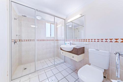 a bathroom with a shower and a toilet and a sink at Airlie Dream in Airlie Beach