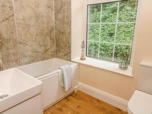 a bathroom with a tub and a sink and a window at Waterfall Cottage in Carnforth