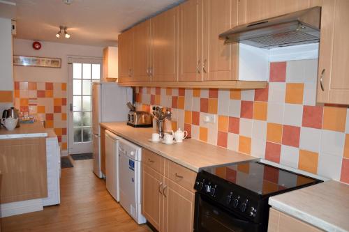 a kitchen with wooden cabinets and a stove top oven at Cornish Townhouse Central Newquay with Parking - Simply Check In in Newquay
