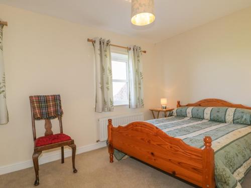 una camera con un letto e una sedia e una finestra di Rowan Cottage a St Bees