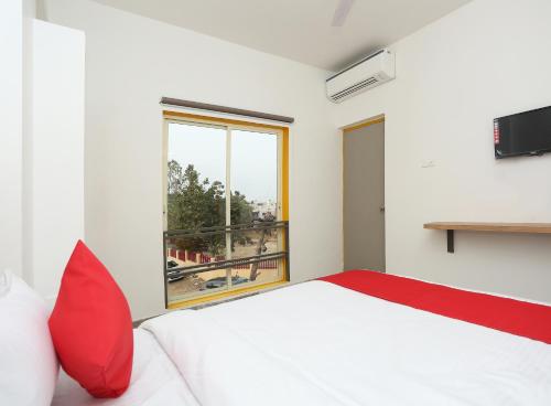 a bedroom with a white bed with red pillows and a window at Stayinn Nest in Bhopal