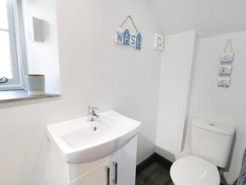 a white bathroom with a sink and a toilet at Owl Cottage in Pwllheli