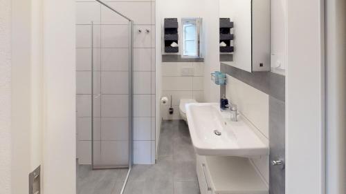 uma casa de banho branca com um lavatório e um chuveiro em Ihr Zuhause am Jakobikirchhof em Goslar