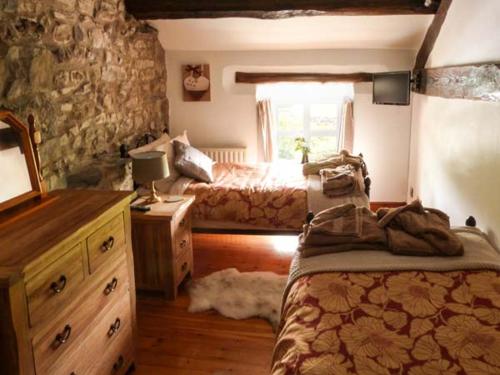 a bedroom with two beds and a stone wall at The Stables in Settle