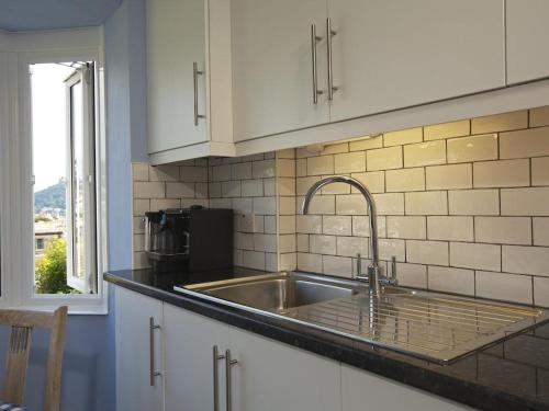 eine Küchentheke mit einem Waschbecken und einem Fenster in der Unterkunft Moonrakers, Clarence Street in Dartmouth
