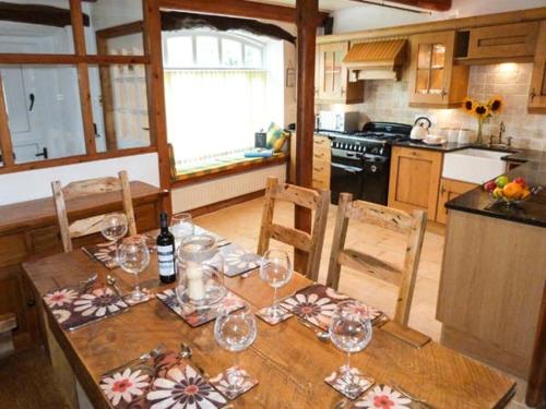 una cocina con una mesa de madera con copas de vino. en The Stables en Settle