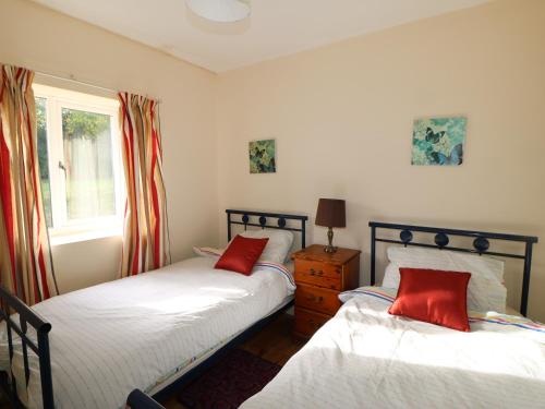 a bedroom with two beds with red pillows and a window at Barforth Hall Lodge in Richmond