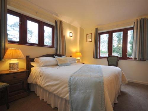 a bedroom with a large bed and two windows at Follis Cottage in Weymouth