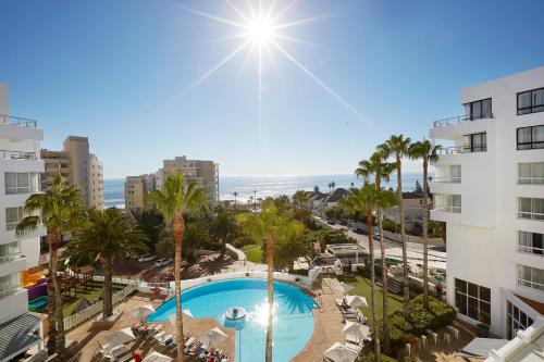 a view of a pool with palm trees and the ocean at President Hotel in Cape Town
