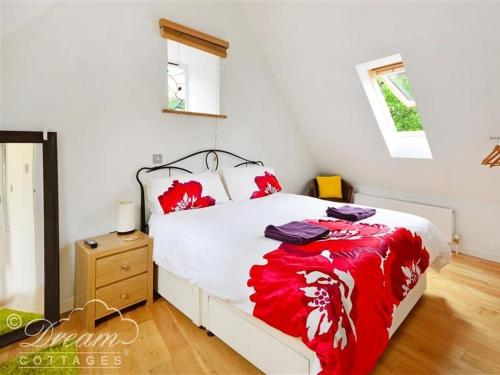 a bedroom with a bed with red and white sheets at Fossil Barn in Chickerell