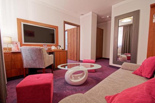 a living room with a couch and a tv at Best Western Plus Hotel Olsztyn Old Town in Olsztyn