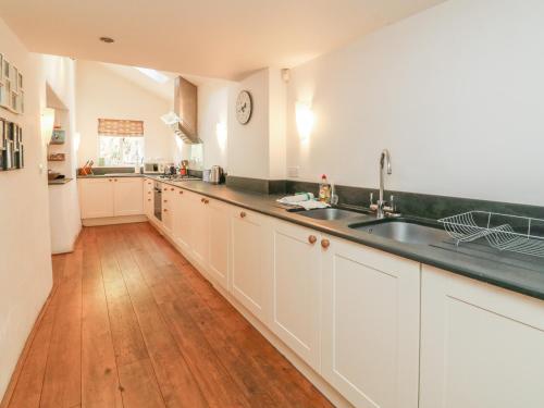 a kitchen with white cabinets and a wooden floor at Old Maids Cottage in Ilfracombe