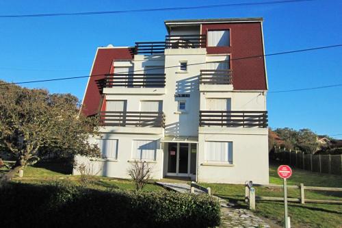 un grand bâtiment blanc avec un toit rouge et un panneau d'arrêt dans l'établissement Appartement Pour 4 Personnes Face A La Plage De La Graviere- Residence San Michele, à Hossegor