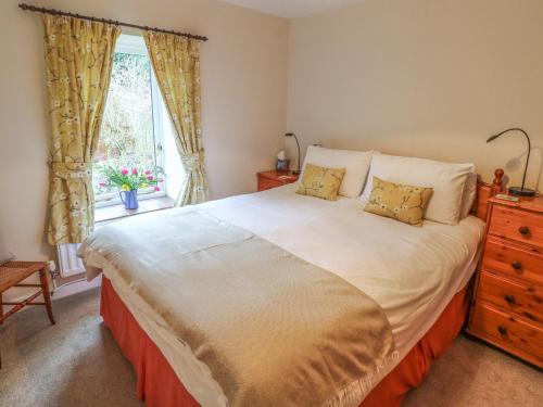 a bedroom with a large bed and a window at Barn Croft Cottage in Matlock