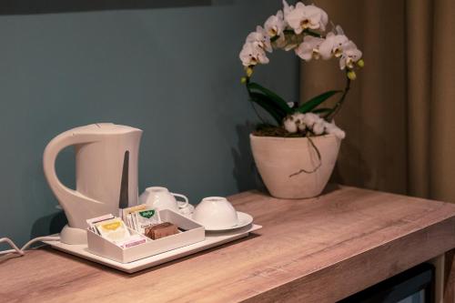 uma mesa com uma chaleira e um vaso com flores em Delight Rooms em Corbetta