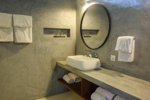 a bathroom with a sink and a mirror and towels at Eva Lanka Hotel - Beach & Wellness in Tangalle