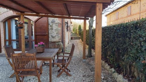 a wooden table and chairs under a wooden pergola at La Limonaia Country House in Monteriggioni