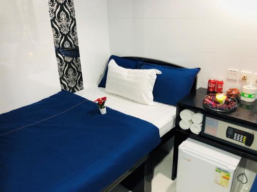 a room with a bed with blue sheets and a microwave at Manila Lounge in Hong Kong