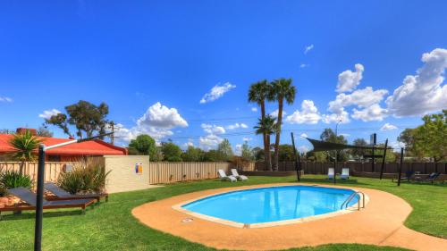 a swimming pool in a yard with a fence at Motel Meneres in Corowa