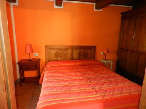 a bedroom with a bed with an orange wall at Agriturismo Vezzano in Chiusi della Verna