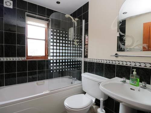 a bathroom with a white toilet and a sink and a tub at Eskview Cottage in Whitby