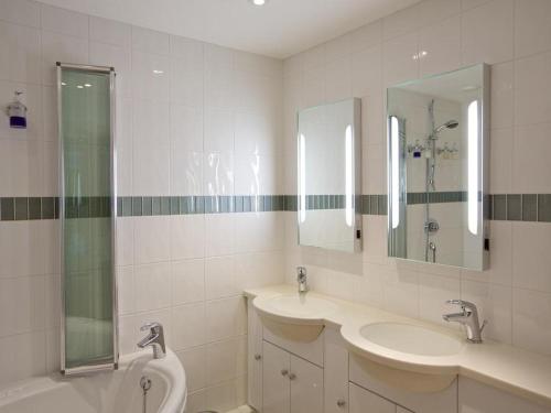 Un baño blanco con dos lavabos y una ducha. en 2 Hamstone Court, en Salcombe