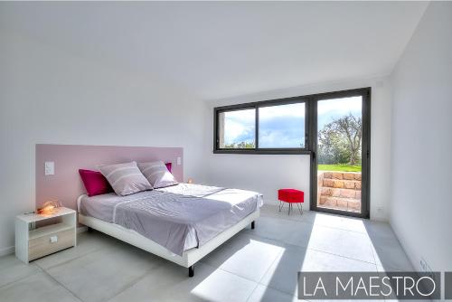 a white bedroom with a bed and a window at Domaine du Peyrouas in Saint-Jeannet