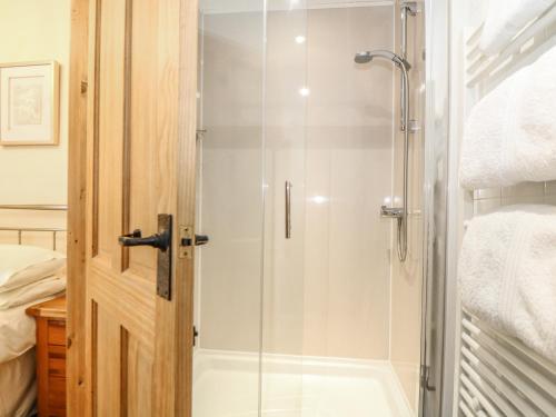 een douche met een glazen deur in een badkamer bij Beech Cottage in Truro