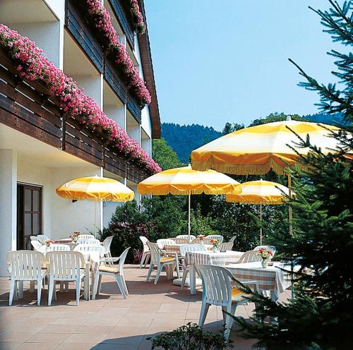 a group of tables and chairs with umbrellas on a patio at Hotel garni zur Weserei in Kandern