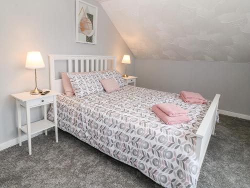 una camera da letto con un letto con cuscini rosa di Buarthau Cottage a Caernarfon