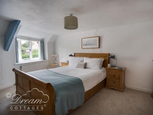 Un dormitorio con una cama grande y una ventana en Lilac Cottage, en Burton Bradstock
