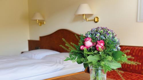 a vase of flowers on a table in a bedroom at Hotel garni zur Weserei in Kandern