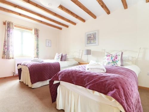 1 dormitorio con 2 camas y mantas moradas en Hawthorn Cottage en Truro