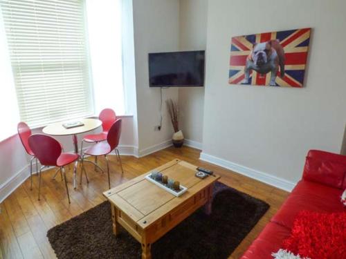 a living room with a red couch and a table at Flat 1 in Bridlington