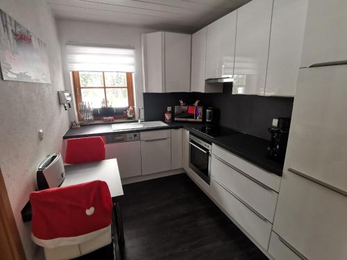 a small kitchen with white cabinets and red chairs at Alpen-Chalet Ehrwald in Ehrwald